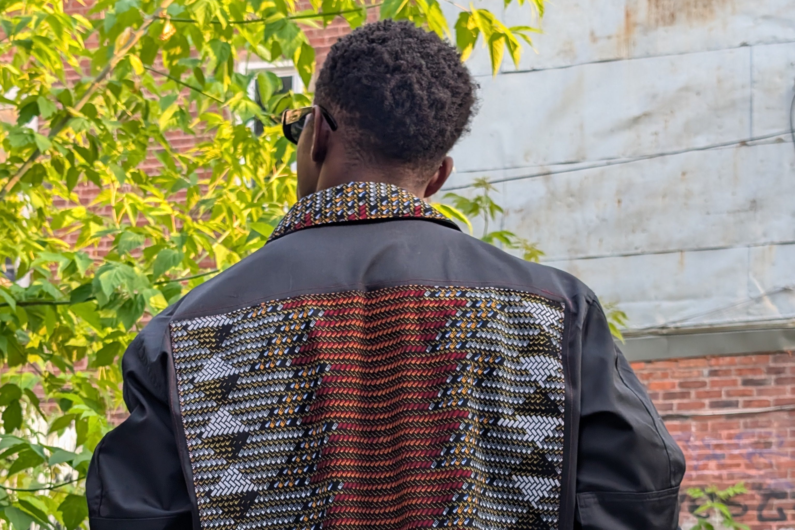 Person wearing a black jacket with a patterned back design in an urban setting